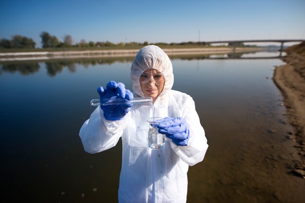Nahaufnahme des Ökologen, der Wasser vom Fluss mit Reagenzglas entnimmt