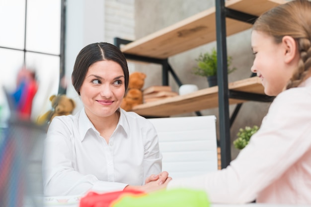 Nahaufnahme des lächelnden weiblichen Psychologen, der blondes Mädchen betrachtet