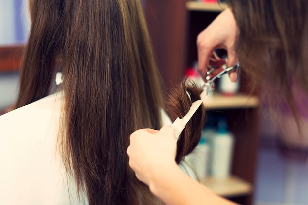 Nahaufnahme des langen Haares, das vom Friseur geschnitten wird