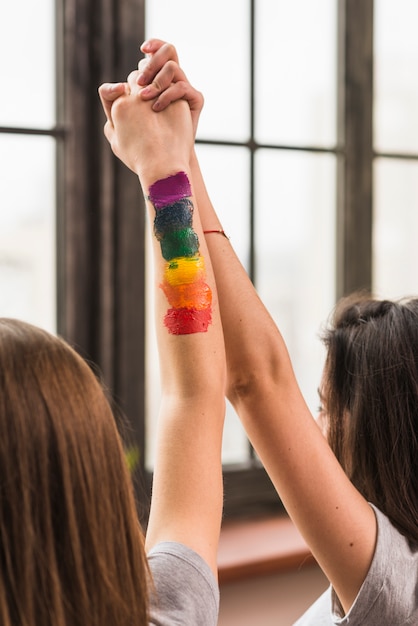 Kostenloses Foto nahaufnahme des lesbischen paares, das sich die hand hält, die ihre arme anhebt