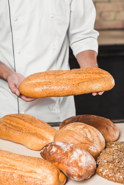 Nahaufnahme des männlichen Bäckers frisches Brot halten