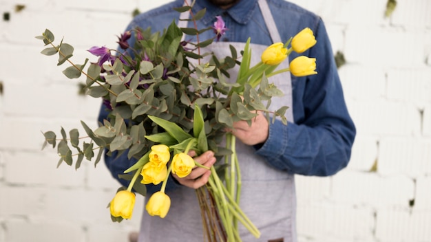 Kostenloses Foto nahaufnahme des männlichen floristen gelbe tulpen und zweige in der hand halten