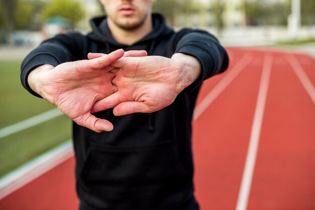 Nahaufnahme des männlichen Sportlers seine Hände auf Rennstrecke ausdehnend