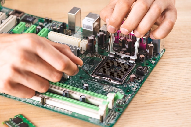 Nahaufnahme des männlichen Technikers CPU-Sockel auf Holztisch reparierend