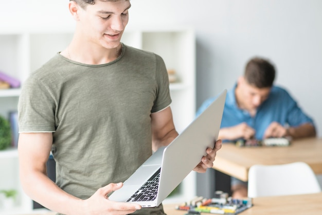 Nahaufnahme des männlichen Technikers den Laptop betrachtend, der in seiner Hand hält