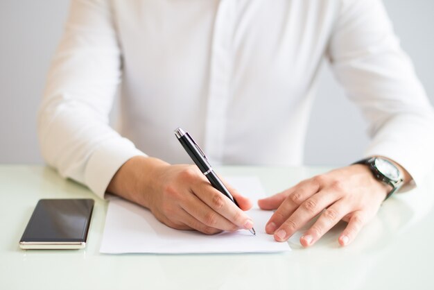 Nahaufnahme des Mannes arbeitend und auf Blatt Papier schreibend