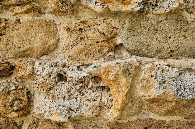 Nahaufnahme des Mauerwerks einer alten weichen Sandsteinmauer, die durch die Zeit erodiert wurde Natursteinidee für Hintergrund oder Interieur