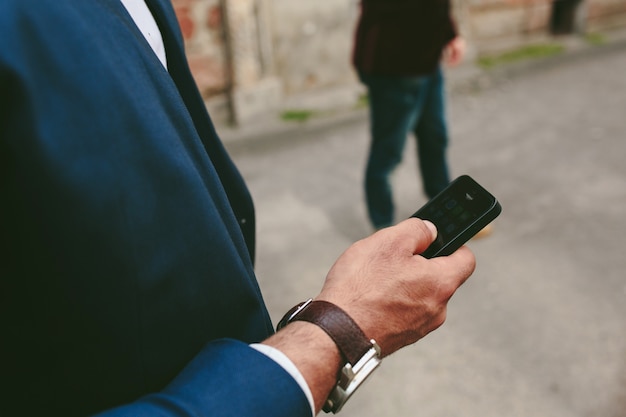 Nahaufnahme des Menschen mit der Uhr mit seinem Handy