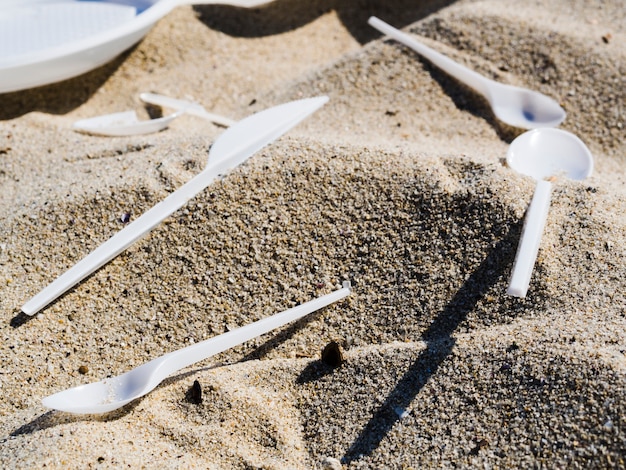 Nahaufnahme des Plastiktischbestecks auf Sand am Strand