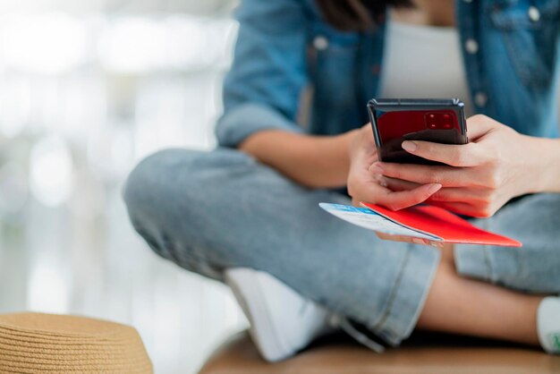 Nahaufnahme des Reisepasses für Reisende in der Hand mit Smartphone für die Online-Überprüfung des Boarding-Abflugs am Flughafenterminal