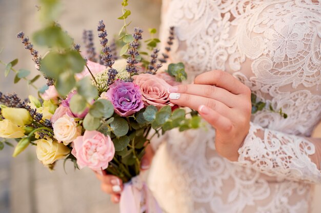Nahaufnahme des rosa und violetten Hochzeitsblumenstraußes in den Händen der Braut