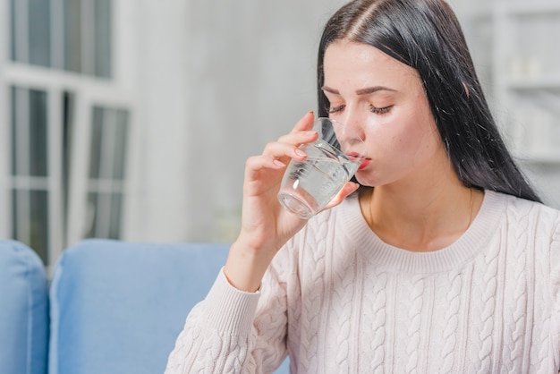 Nahaufnahme des schönen Trinkwassers der jungen Frau vom Glas