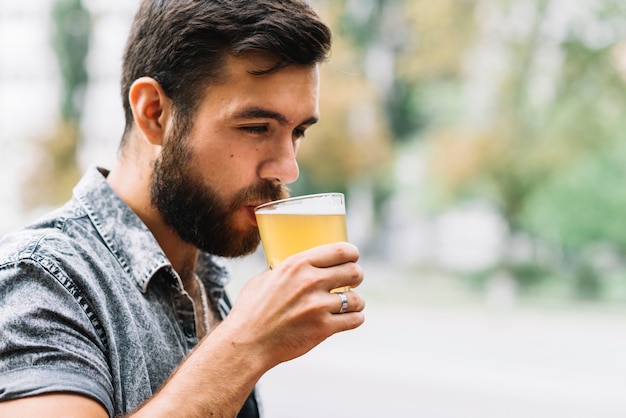 Nahaufnahme des trinkenden Glases des Mannes Bier am Freien