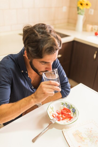 Nahaufnahme des trinkenden Glases des Mannes Wasser in der Küche