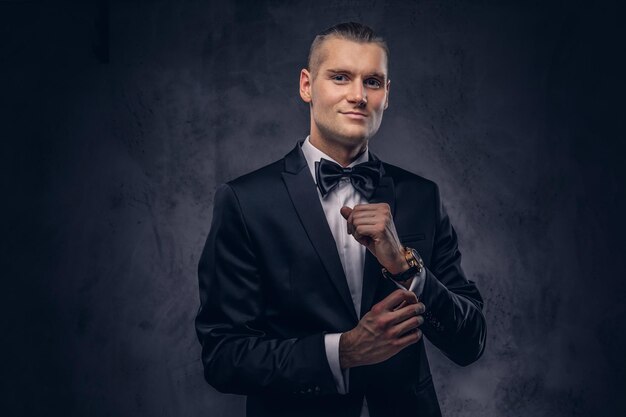 Nahaufnahme, ein Porträt eines gutaussehenden, stilvollen Mannes in einem eleganten schwarzen Anzug vor dunklem Hintergrund.