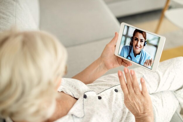 Nahaufnahme einer älteren Frau, die einen Videoanruf mit ihrem Arzt über ein Touchpad führt