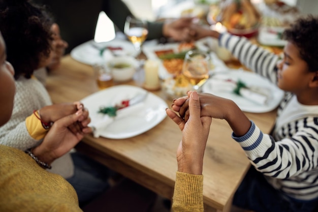 Nahaufnahme einer afroamerikanischen Familie, die vor dem Weihnachtsessen im Speisesaal Anmut sagt