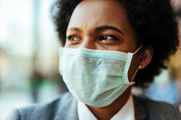 Nahaufnahme einer afroamerikanischen Frau, die eine schützende Gesichtsmaske trägt