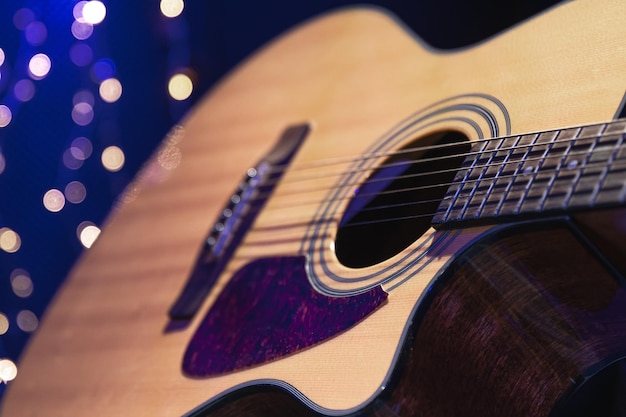 Kostenloses Foto nahaufnahme einer akustikgitarre auf dunklem hintergrund mit bokeh-lichtern