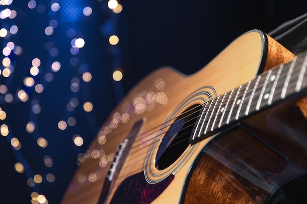 Kostenloses Foto nahaufnahme einer akustikgitarre auf dunklem hintergrund mit bokeh-lichtern