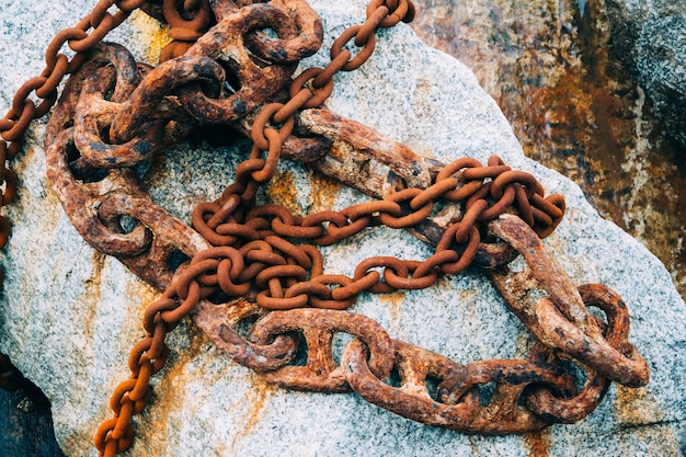 Nahaufnahme einer alten rostigen Kette, die auf den Felsen gelegt wird