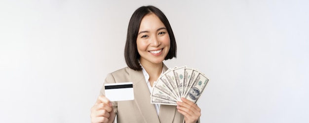 Nahaufnahme einer asiatischen Geschäftsfrau im Büro, die Kreditkarte und Gelddollar im Anzug o zeigt
