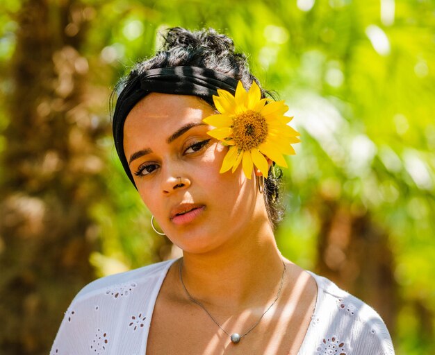 Nahaufnahme einer attraktiven Brasilianerin mit Sonnenblumen im Park