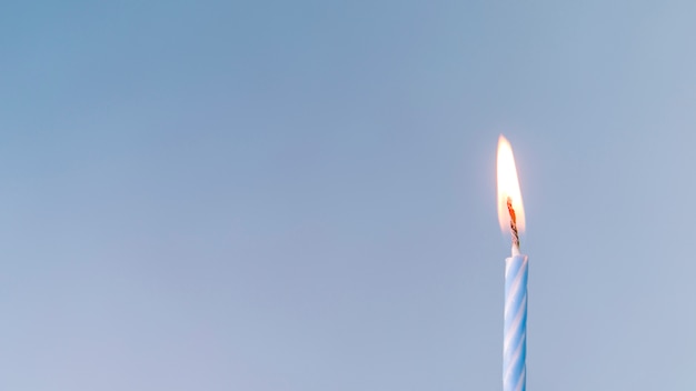 Nahaufnahme einer belichteten Kerze gegen blauen Hintergrund