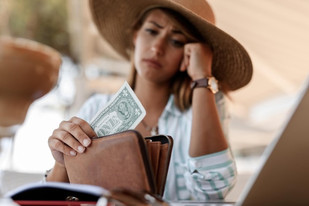 Nahaufnahme einer besorgten Frau, die einen Dollarschein in ihrer Brieftasche hat