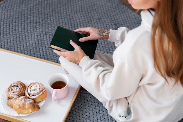 Nahaufnahme einer Frau auf dem Boden, die ein Buch hält