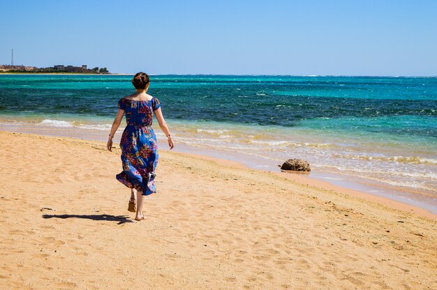 Nahaufnahme einer Frau, die an einem sonnigen Tag am Strand spazieren geht