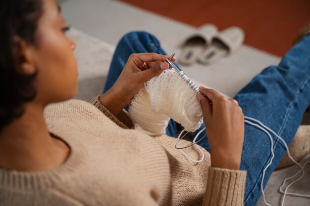 Nahaufnahme einer Frau, die auf dem Boden strickt