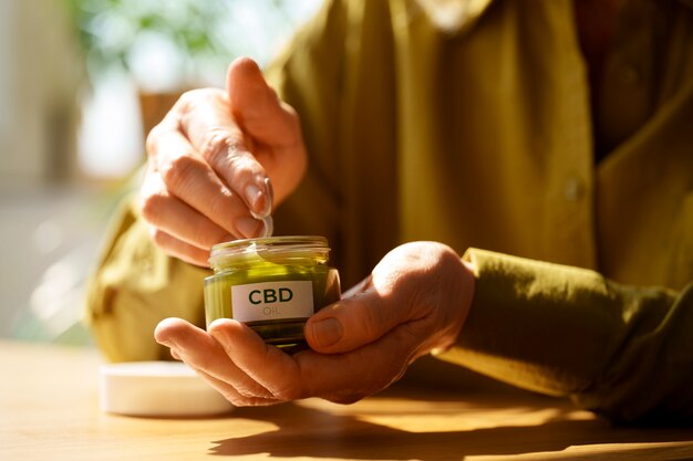 Nahaufnahme einer Frau, die CBD-Creme gegen Schmerzen verwendet