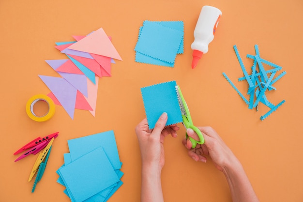 Nahaufnahme einer Frau, die das Papier mit scissor auf farbigem Hintergrund schneidet