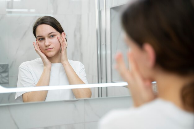 Nahaufnahme einer Frau, die Gesichtscreme aufträgt