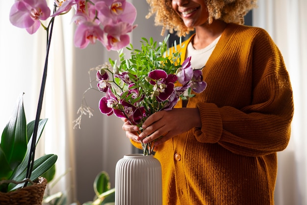 Nahaufnahme einer Frau, die ihr Zuhause mit Orchideen dekoriert
