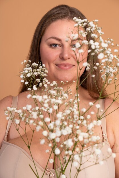 Nahaufnahme einer Frau, die mit Blumen posiert