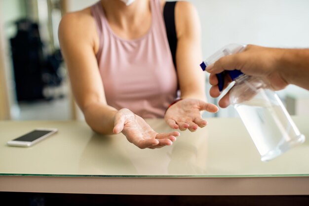 Nahaufnahme einer Frau, die sich an der Rezeption die Hände desinfizieren lässt