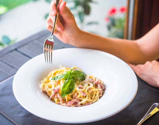 Nahaufnahme einer Frau, die Spaghettis mit Gabel isst