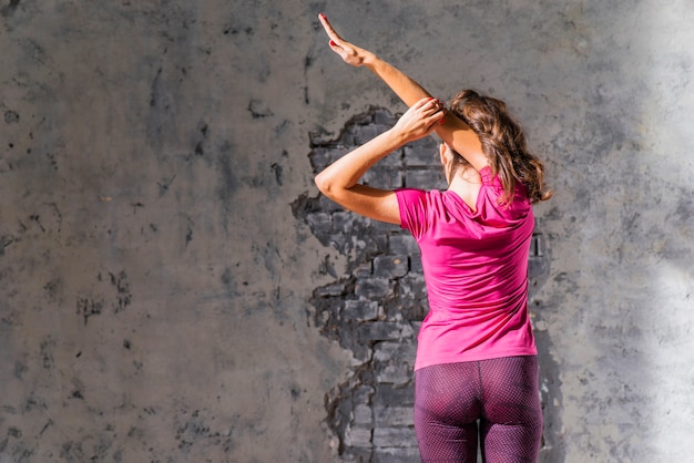 Nahaufnahme einer Frau, die vor der Wand steht, die ihren Arm ausdehnt