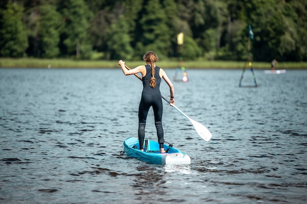 Nahaufnahme einer Frau in einem schwarzen Sportanzug, die auf einem See im Sup-Wettbewerb paddelt
