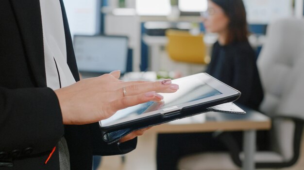 Nahaufnahme einer Frau mit digitalem Tablet mit Touchscreen für Geschäftsprojekt. Frau mit Firmenjob, die modernes Gadget verwendet, um an der Management- und Marketingstrategie im Büro zu arbeiten.