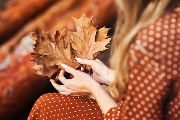 Nahaufnahme einer Frau mit einem Haufen herbstlicher Blätter