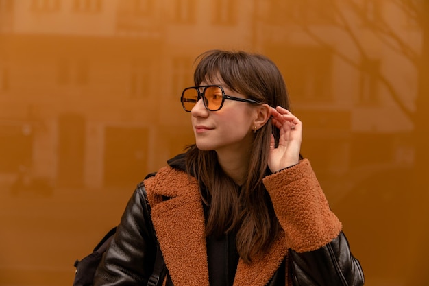 Nahaufnahme einer Frau mit orangefarbener Sonnenbrille in der Nähe der Wand, wegsehen