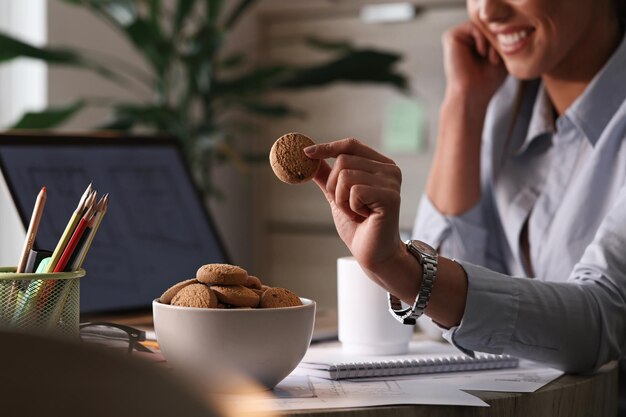 Nahaufnahme einer Geschäftsfrau, die in einer Pause in ihrem Büro Kekse isst