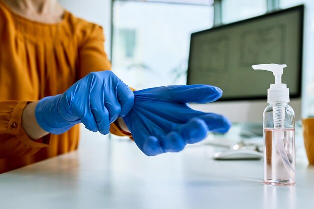 Nahaufnahme einer Geschäftsfrau, die sich auf die Arbeit vorbereitet und im Büro Schutzhandschuhe anzieht