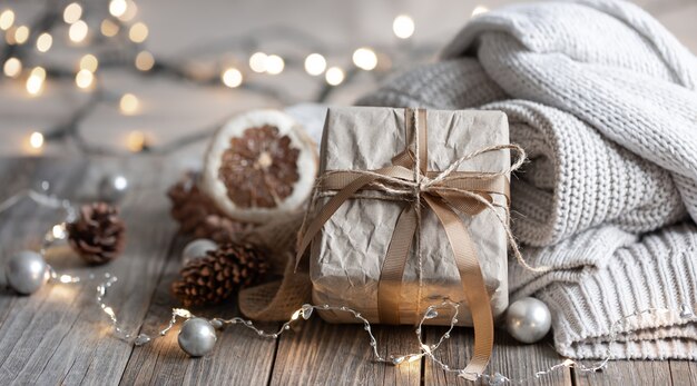 Nahaufnahme einer Geschenkbox, Details eines festlichen Weihnachtsdekors und gestrickte Elemente auf einem unscharfen Hintergrund mit Bokeh.