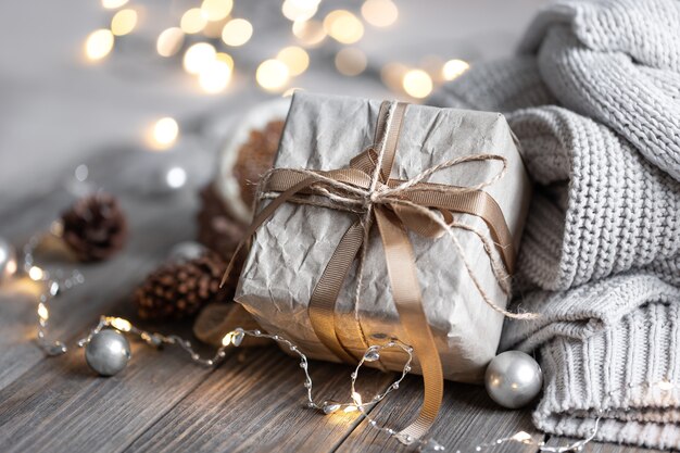 Nahaufnahme einer Geschenkbox, Details eines festlichen Weihnachtsdekors und gestrickte Elemente auf unscharfem Hintergrund mit Bokeh.