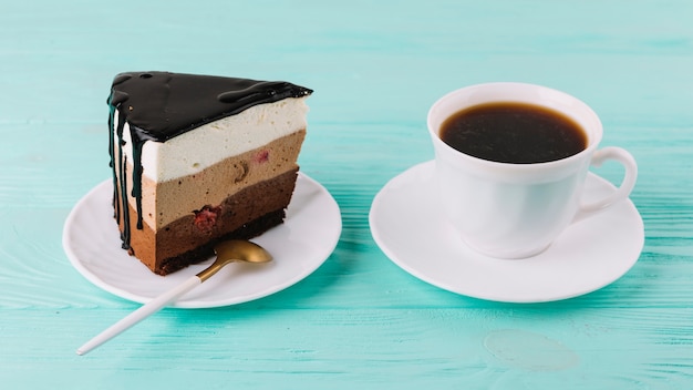 Nahaufnahme einer geschmackvollen sahnigen Torte mit Löffel und Tasse Tee