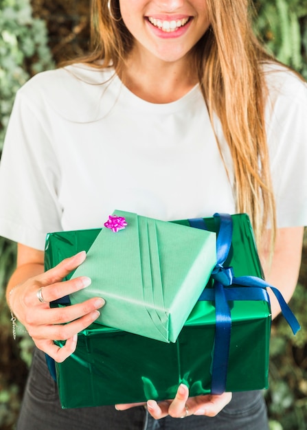 Nahaufnahme einer glücklichen Frau, die grüne Geschenkboxen hält